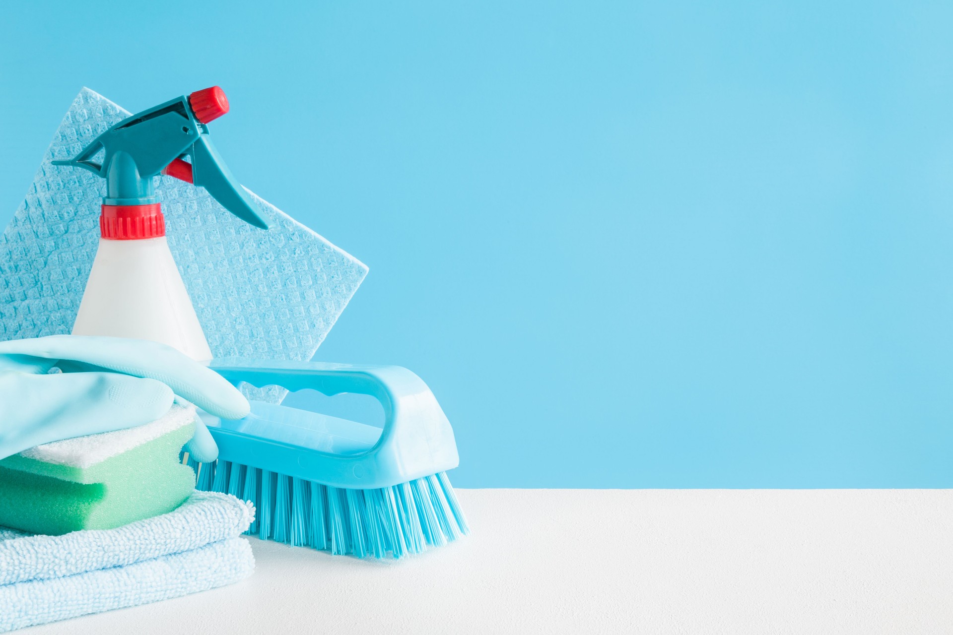 Cleaning set for different surfaces in kitchen, bathroom and other rooms. Empty place for text or logo on blue background. Cleaning service concept. Early spring regular clean up. Front view.